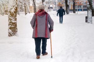 Elderly woman using walking stick ferrule in winter